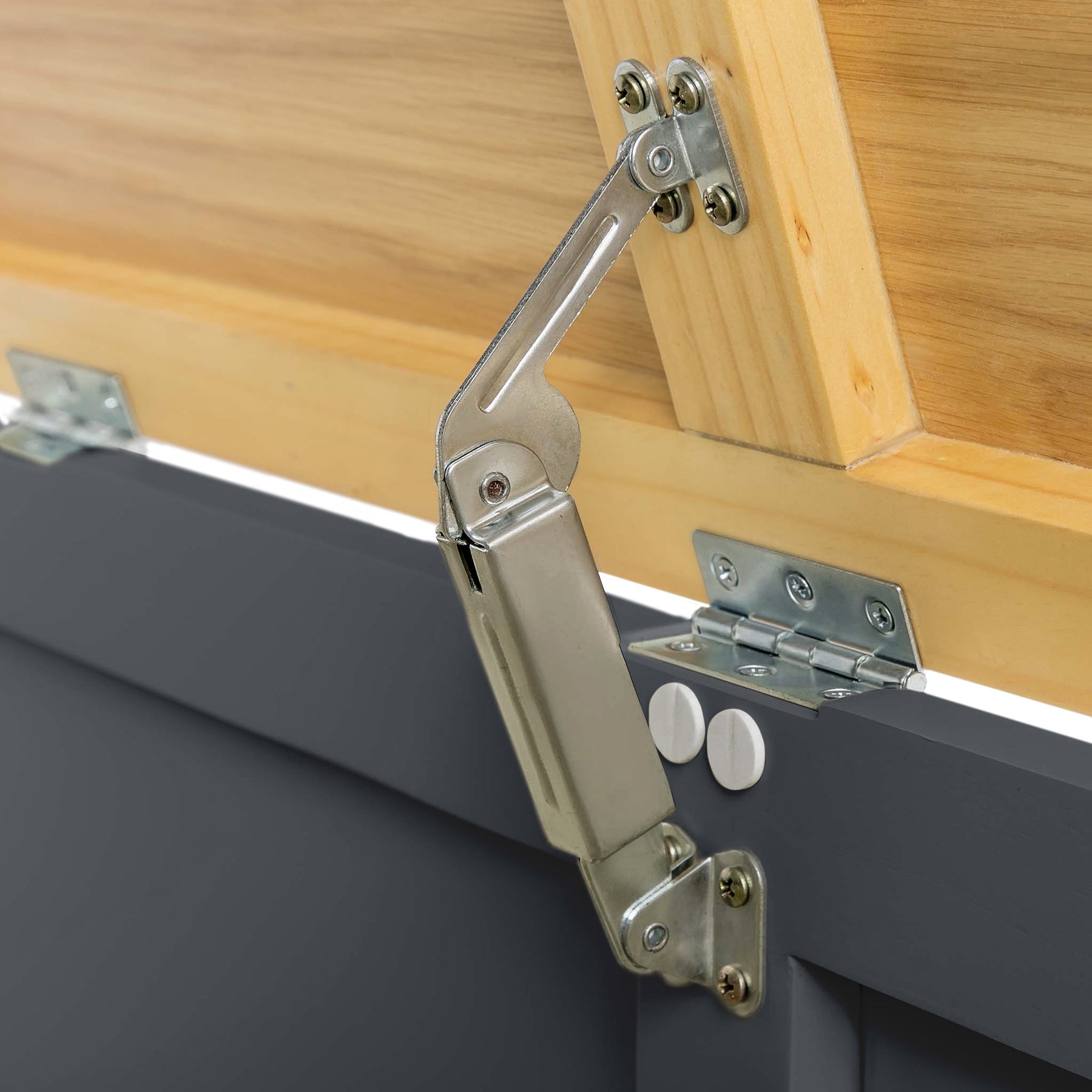 A metal hinge connects a wooden panel to a gray surface, allowing the panel to pivot or remain upright, against a neutral background.