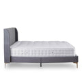 A single bed with mattress, featuring a grey upholstered headboard, rests stationary against a plain white background.