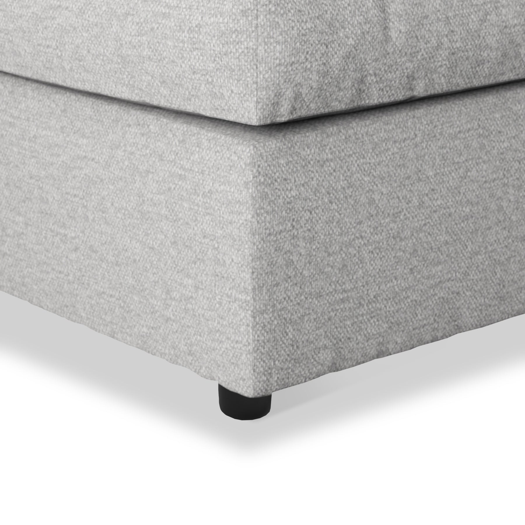A grey fabric ottoman with a visible cushion seam, resting on a black round leg; isolated on a white background.