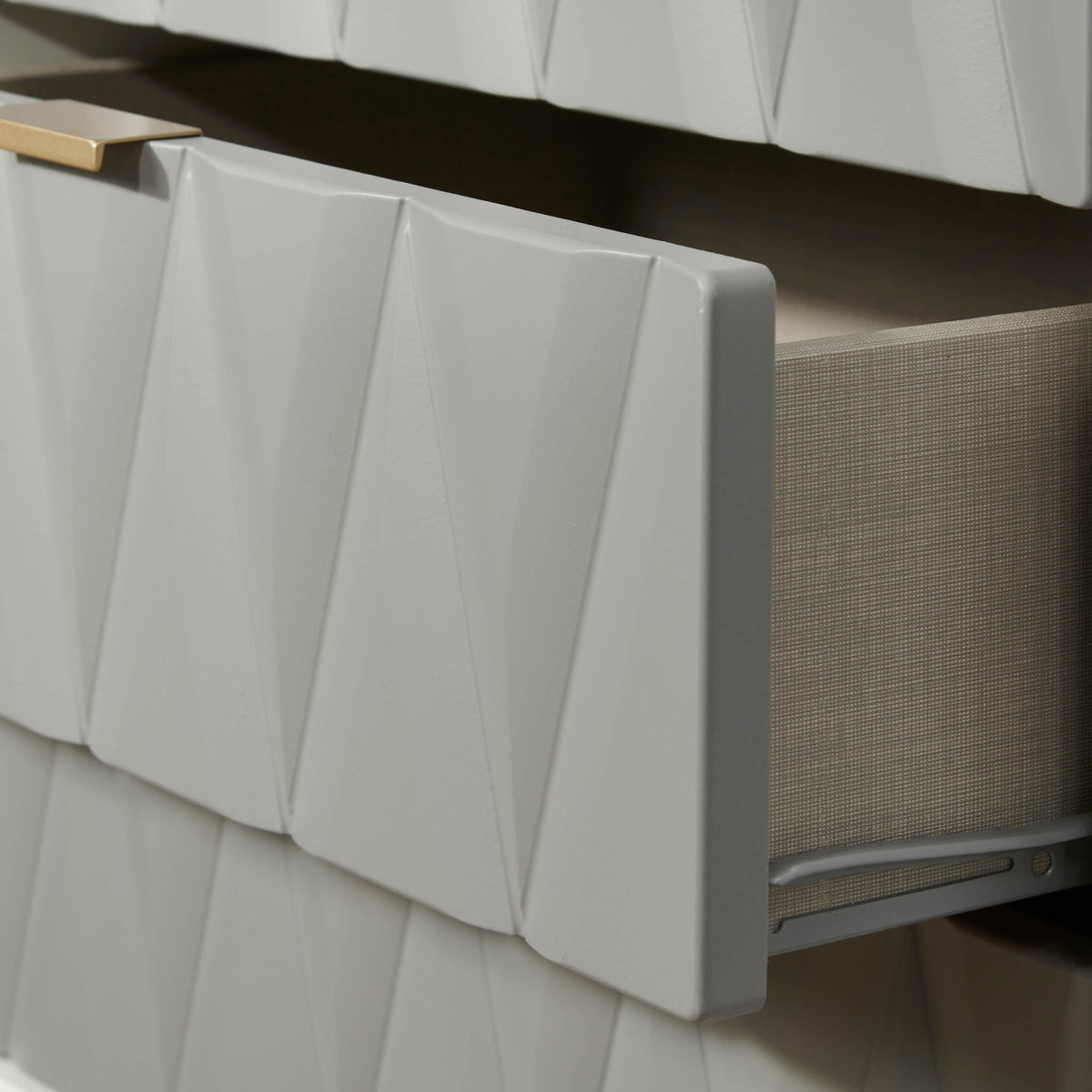 A white textured radiator cover with a geometric pattern, partially obscuring a beige radiator, against a white tiled wall with dark grout.