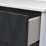 A black computer monitor sits on a white desk adjacent to a gray fabric panel partition, suggesting an office setting.