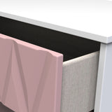 A pink geometric-patterned panel sits adjacent to a textured grey chair, near a desk with a white top against a dark background.