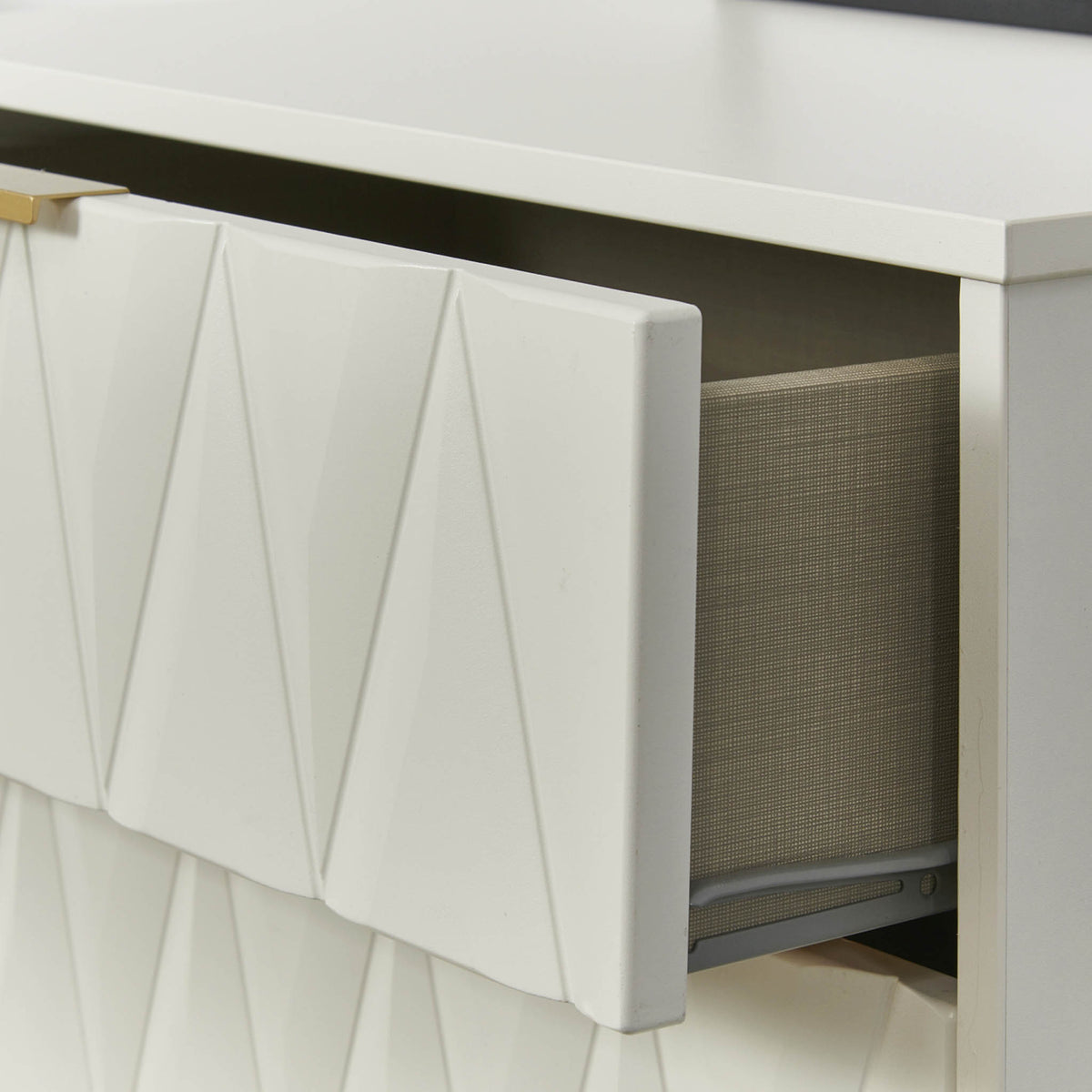 An open white drawer with a geometric pattern partially reveals its gray fabric contents against a white background.