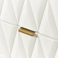 A golden door handle interrupts a geometric pattern of white, three-dimensional triangles on a wall.