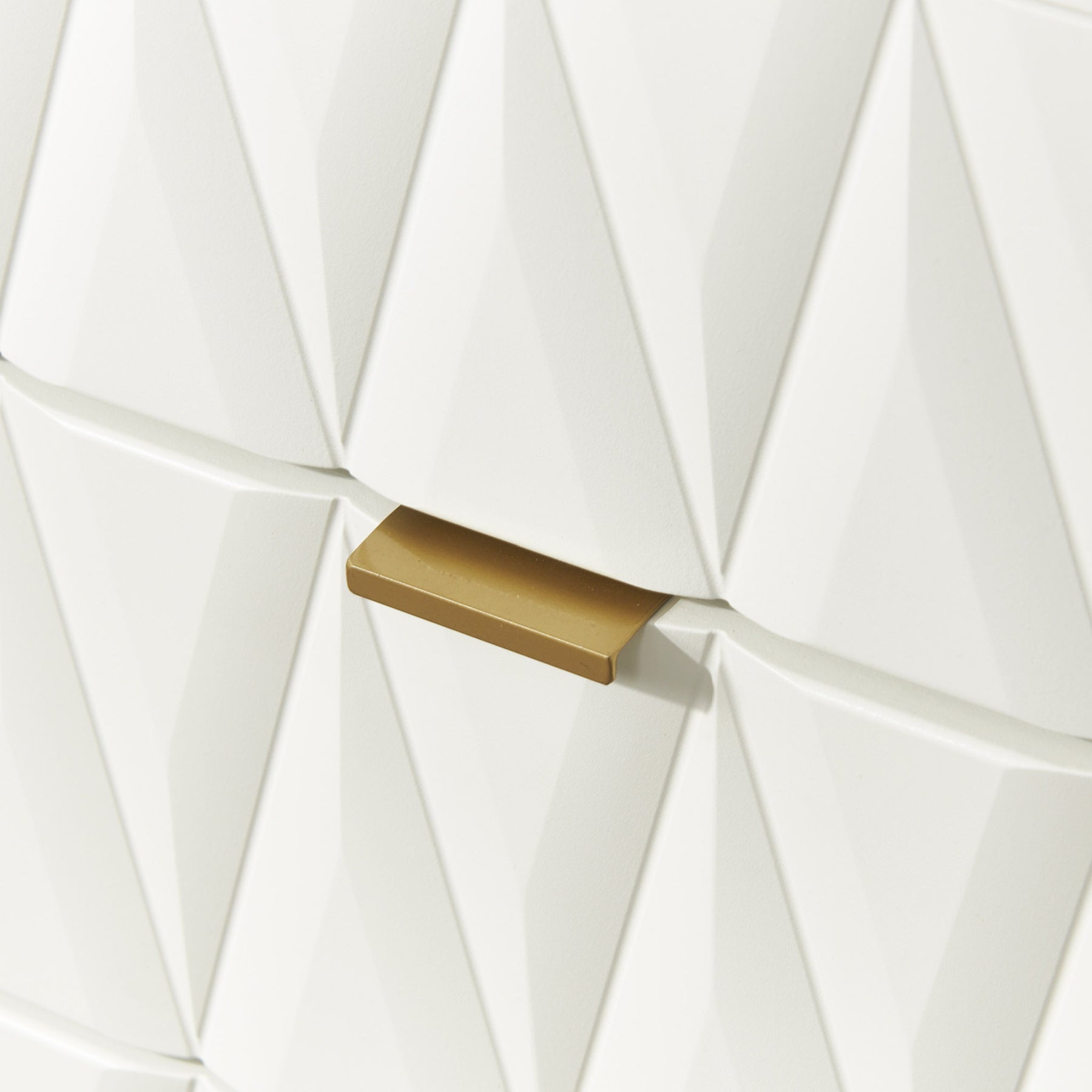 A golden door handle interrupts a geometric pattern of white, three-dimensional triangles on a wall.